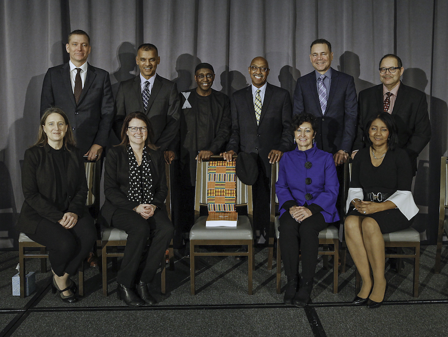 The Council of Parties is the group of appointed commissioners who led the Restorative Inquiry. Front row, from left to right: Jennifer Llewellyn, Jean Flynn, Chief Judge Pam Williams and Deborah Emmerson. Back row, left to right: Michael Dull, Dean Smith, Wayn Hamilton, George Gray, Tony Smith and Gerald Morrison. The empty chair represents the late Joan Jones, a Council member and celebrated community activist who passed away in April 2019.